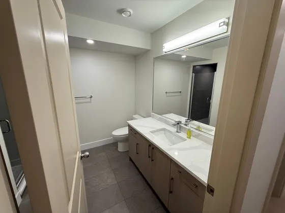 Renovated bathroom with a quartz vanity, framed mirror, and glass-enclosed shower