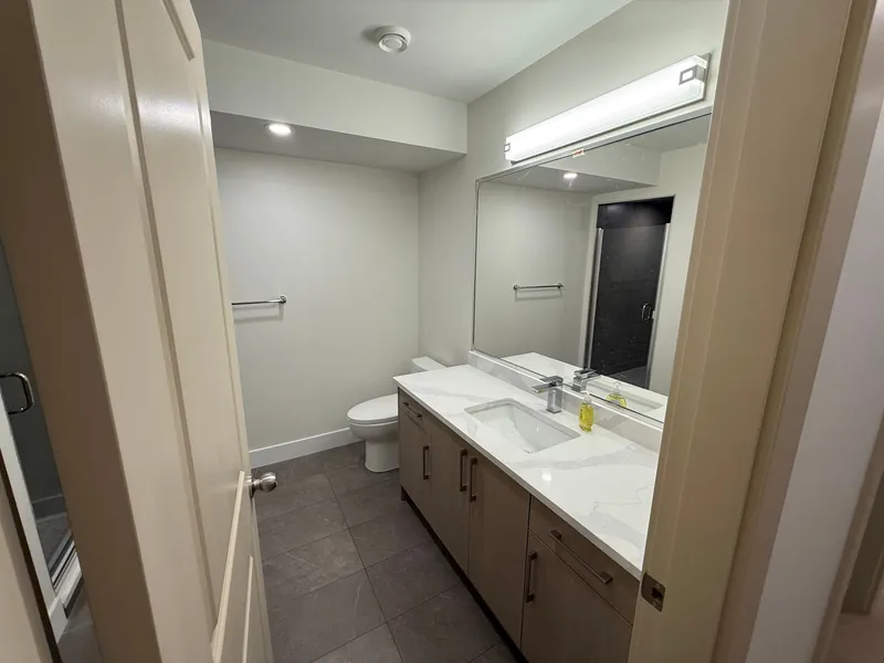 Renovated bathroom with a quartz vanity, framed mirror, and glass-enclosed shower