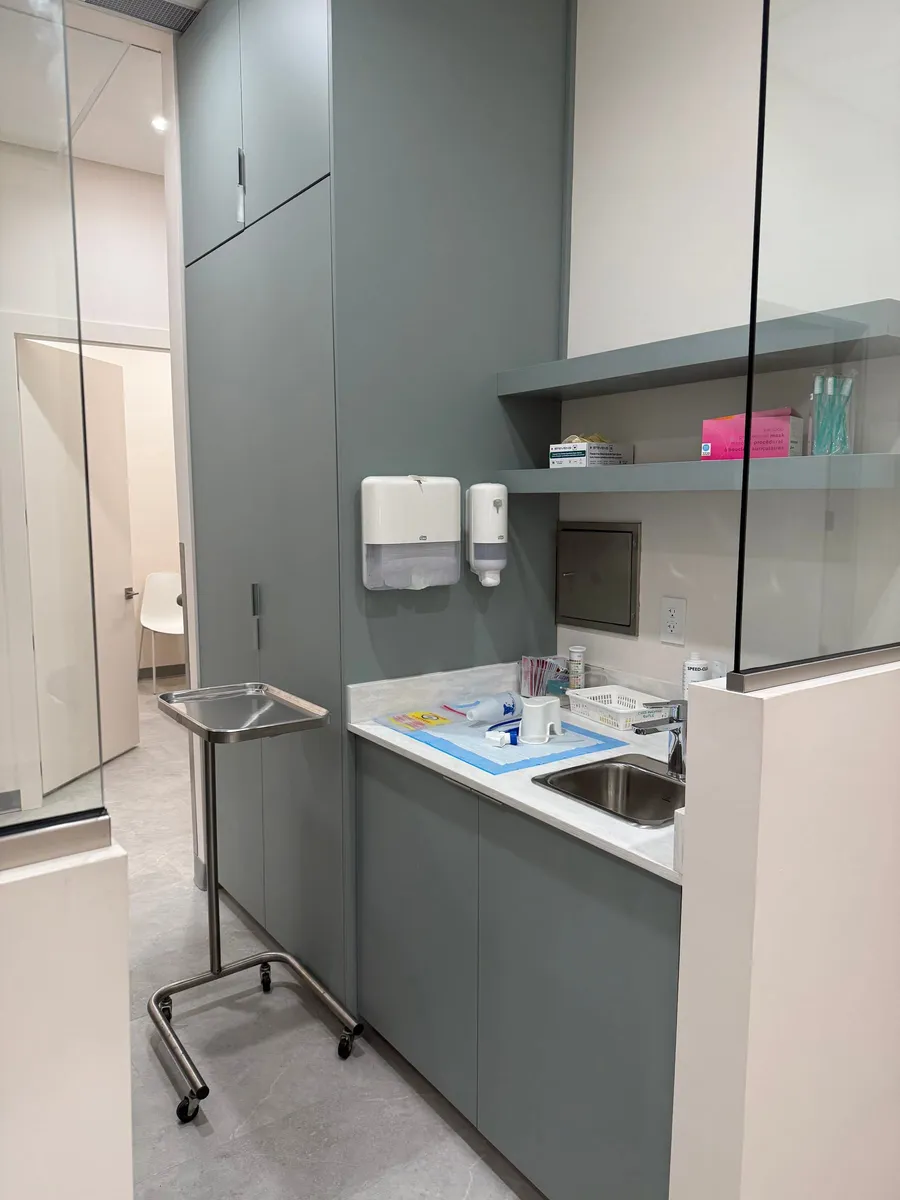 Completed exam room with built-in cabinetry, integrated sink, and glass partition