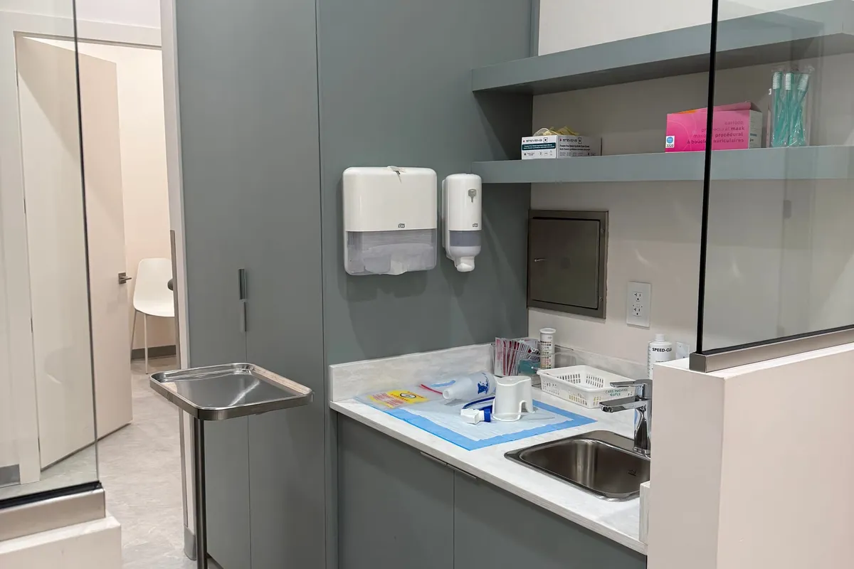 Completed exam room with built-in cabinetry, an integrated sink, and a glass partition