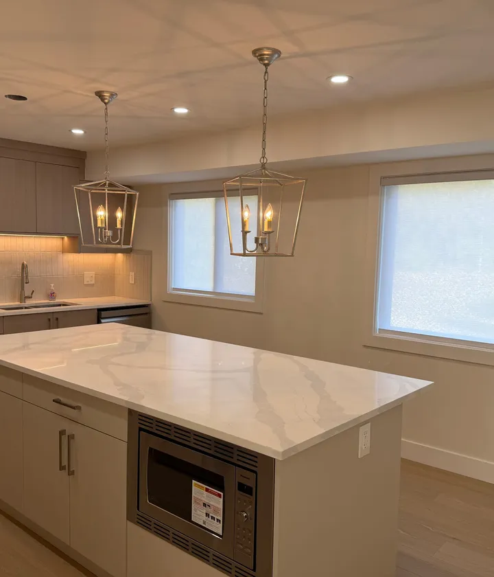 Renovated kitchen with a white quartz waterfall island and taupe shaker cabinetry