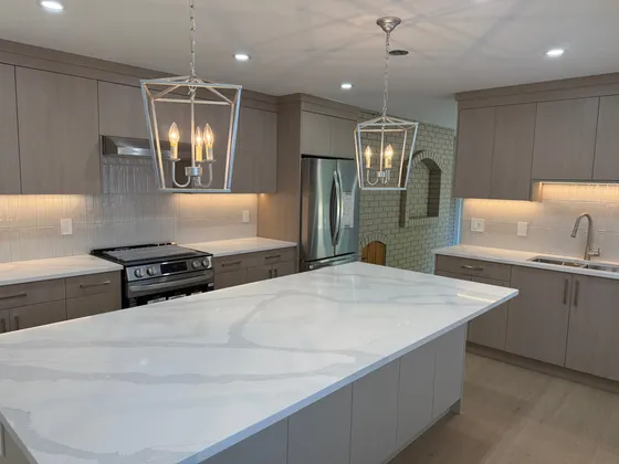 Kitchen range wall with taupe cabinetry, tiled backsplash, and a brick-lined arch niche